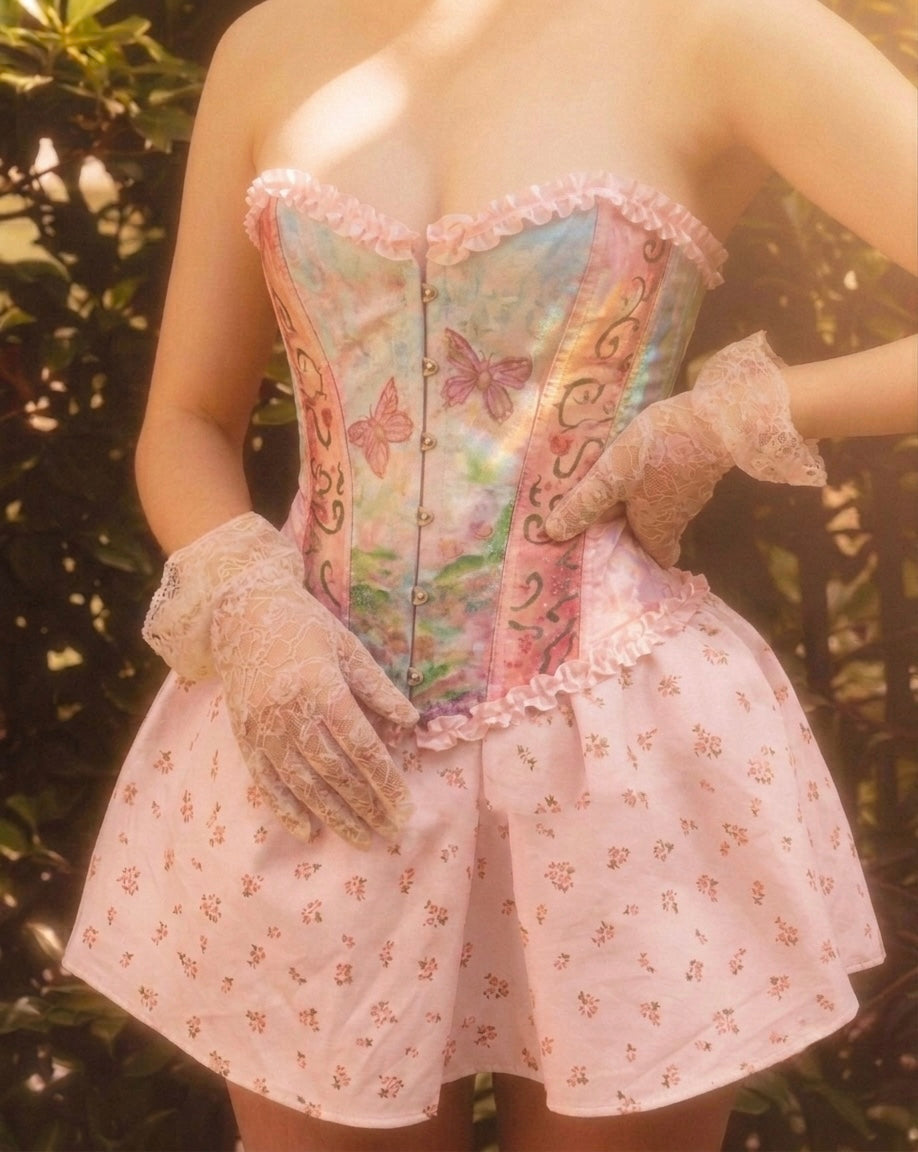 The Fairytopia Corset by Closet Albita. A fairycore structured bustier featuring hand-painted butterflies—not embroidered—with pink ruffles and a nostalgic aesthetic.
