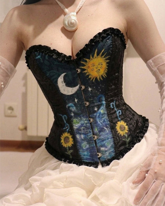 A close-up of a model wearing a black corset with a Van Gogh-inspired night sky print featuring a yellow sun, crescent moon, and sunflowers, paired with a white ruffled skirt and sheer white gloves.